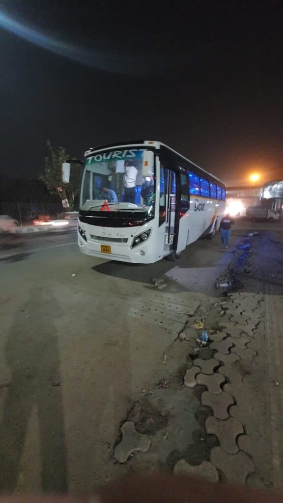 A white and blue bus with the words "Sagar Travels" on its side, parked on a street
